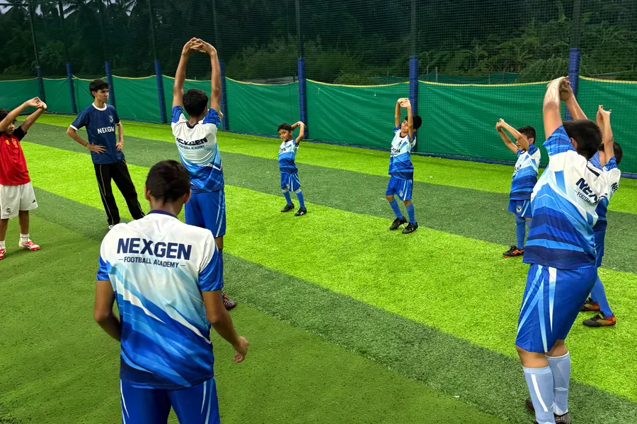 NexGen players warming up on the pitch under coach supervision